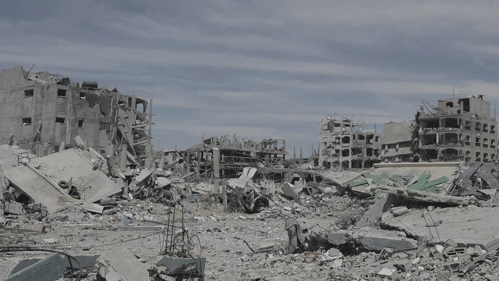Sönderbombade flervåningshus och fält av betongbråte i flyktinglägret Jabalia i norra Gaza under en grå himmel.